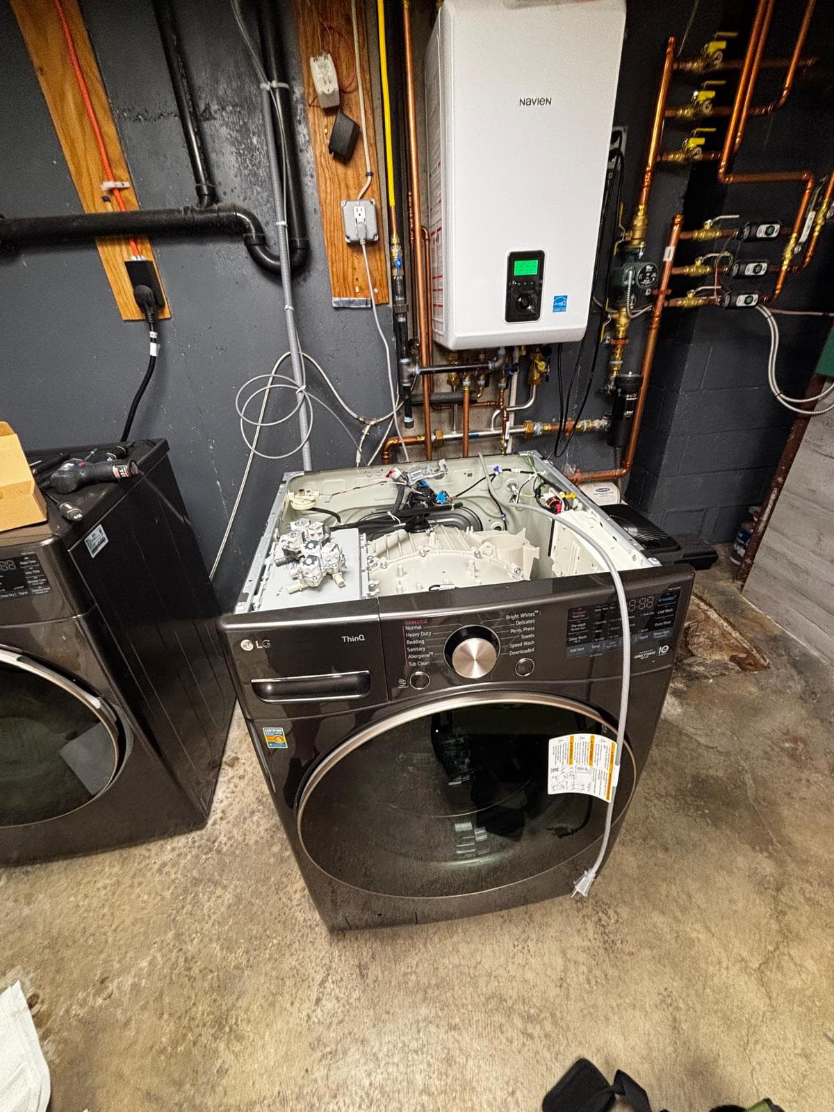 LG ThinQ front-load washing machine internal components exposed during repair in Connecticut basement utility room